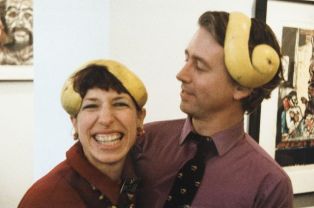 Karen Feinberg and Roger Haile wearing grapefruit peel caps at exhibition opening.