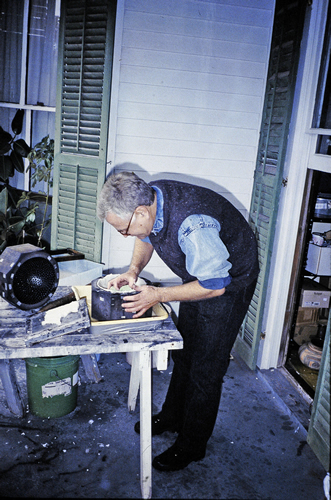 Pressing handmade paper into wooden inked bowl to print HIV Condom Piñatas